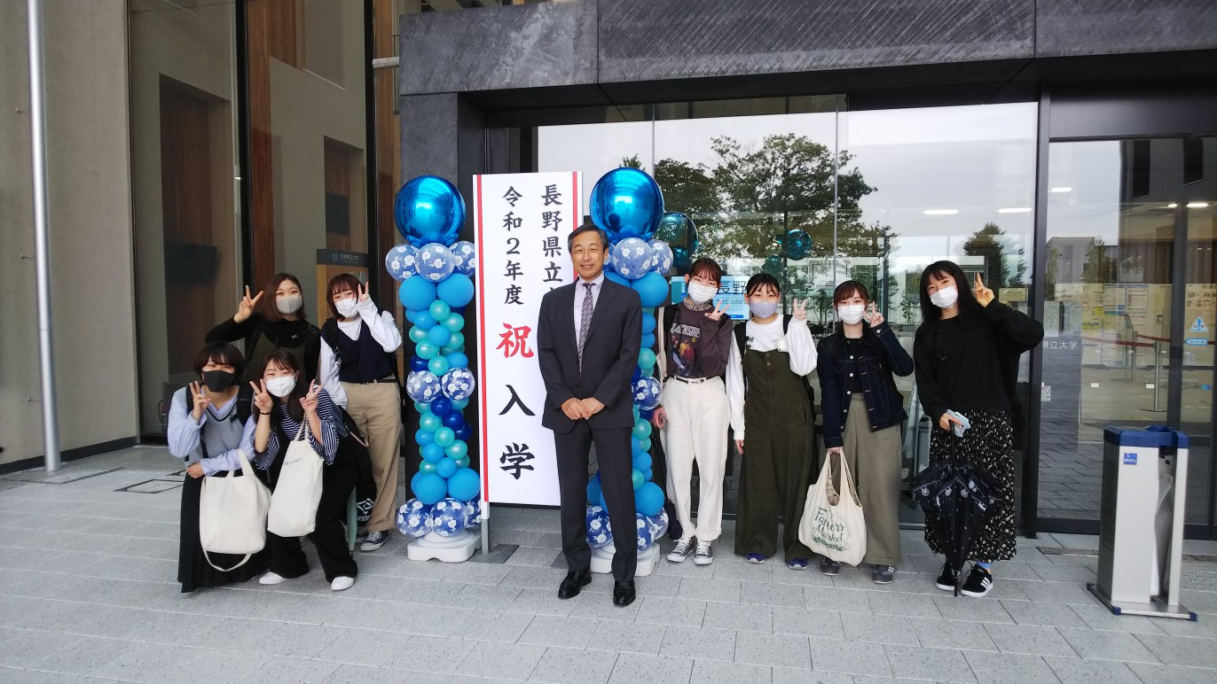 バルーンアート前で学長と写真撮影をする新入生たち